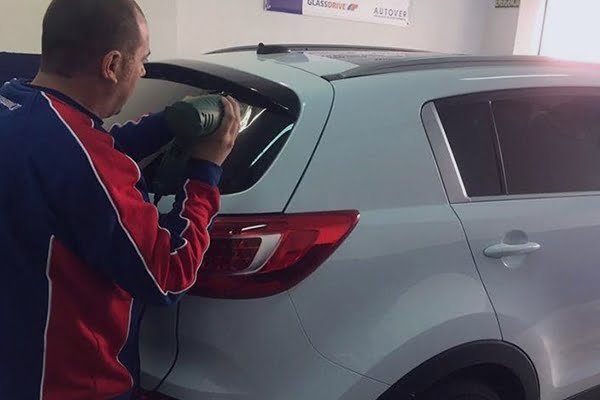 Técnico trabajando en la luna trasera de un coche